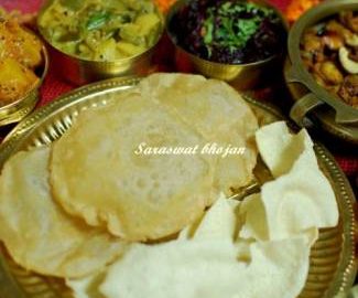 close up view of Saraswat recipes like Beetroot sukke, Pooris Appalam Madras cucumber relish, Savoury buttermilk pancakes, Coconut rice,Pumpkin phodyo, pappadam, Kairas , served on a brass platter