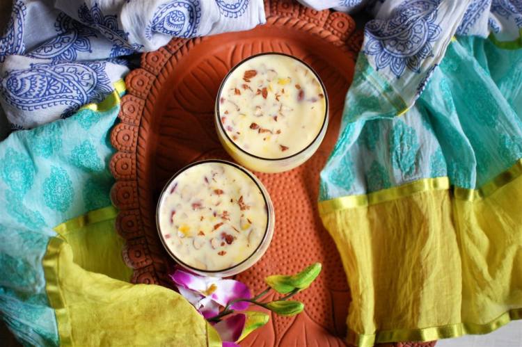 benefits of kesar badam doodh, almond saffron milk recipe garnished with almonds, served in 2 glasses on a clay platter