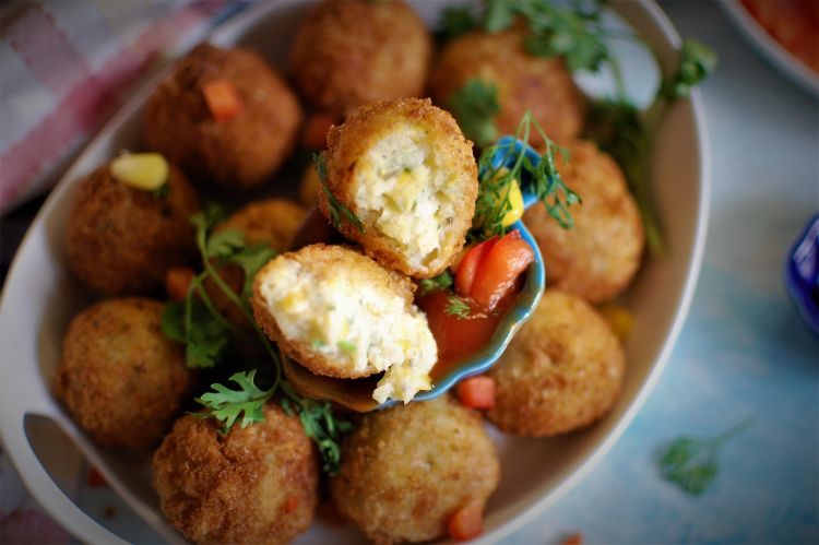 close up view of corn cheese balls, cut into half and showing the cheese melted, served with tomato ketchup