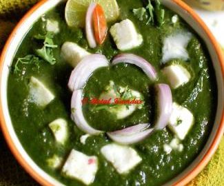 Close-up view of palak paneer garnished with onion slices and a slice of lemon