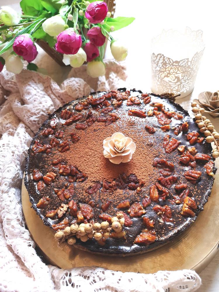 overhead photo of incredibly delicious chocolate coffee tart, with chocolate ganache, dusted with cocoa powder and topped with caramelised pecan nuts