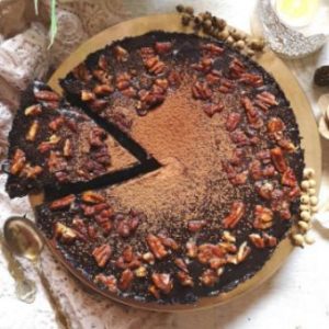 overhead photo and a cut slice of of incredibly delicious chocolate coffee tart, with chocolate ganache, dusted with cocoa powder and topped with caramelised pecan nuts