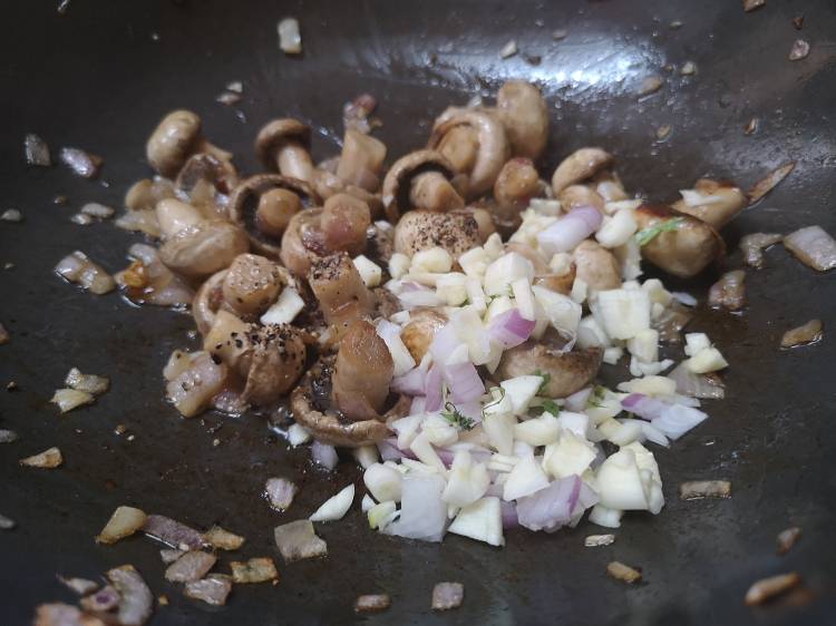 adding finely chopped garlic to prepare garlic mushroom