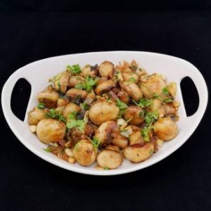 close up view of garlic mushrooms garnished with finely chopped coriander leaves, served on a white platter
