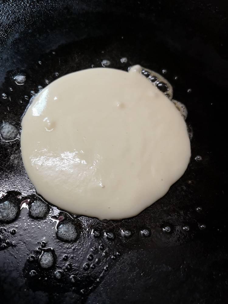 Pancakes batter spread on hot griddle for Nutella pancake recipe