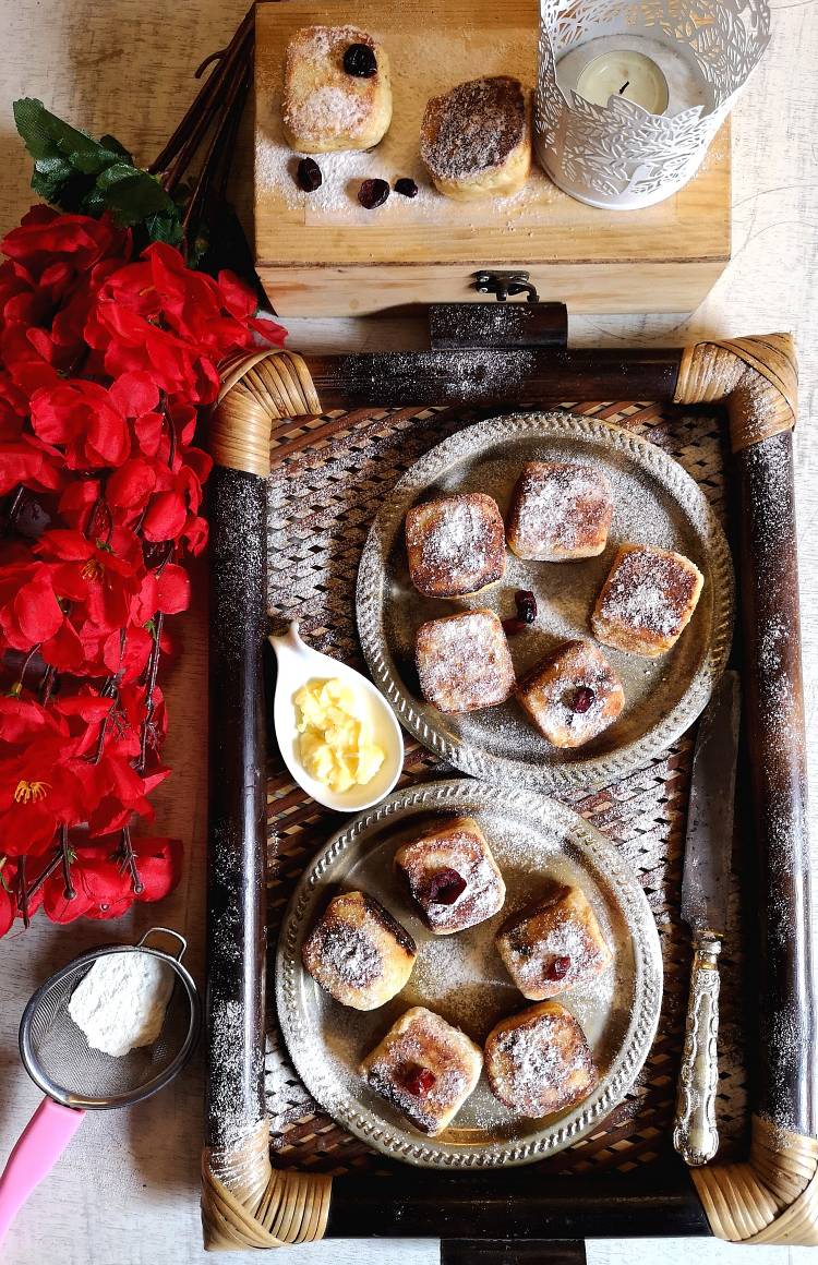 Overhead photo of incredibly delicious Syrniki dusted with icing sugar, served with butter, dry red flowers used as an element for food styling, how to make Russian Cheese