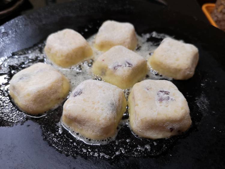 adding melted butter to the pan of syrniki dough squares and cooking them on cast iron tawa