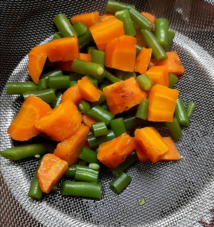 straining boiled carrots and french beans in a strainer, mix veg kebab