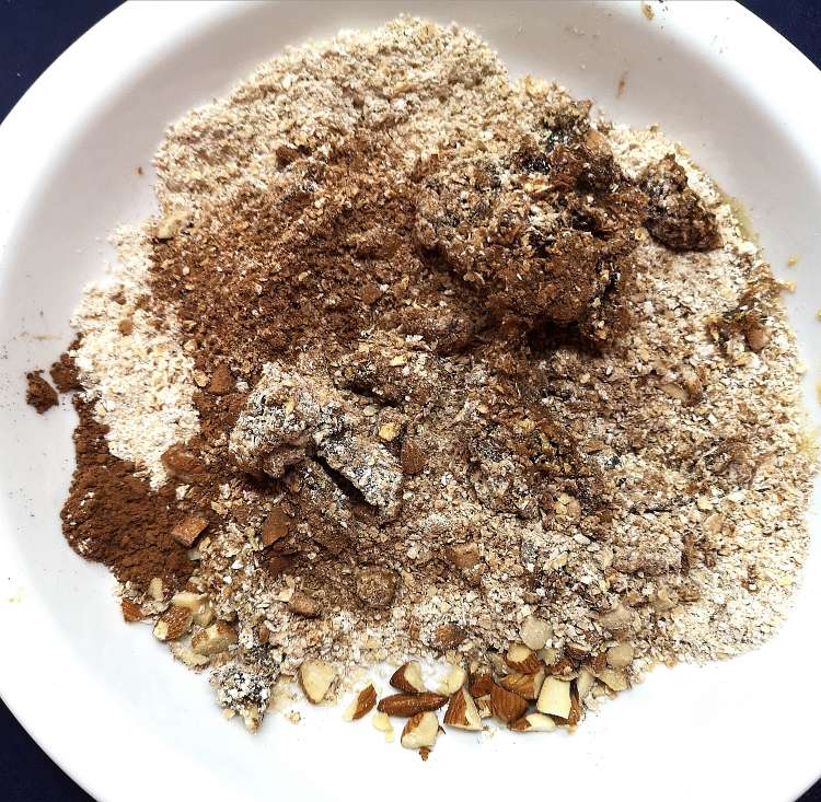 mixing oats, coco powder, honey, almonds, dates for Brownie Energy Bites recipe