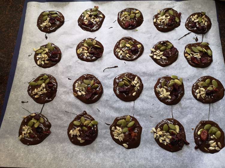 Recipe of Chocolate Mendiants, garnishing dark chocolate mendiants with flax seeds, pumpkin seeds, cranberries and sunflower seeds