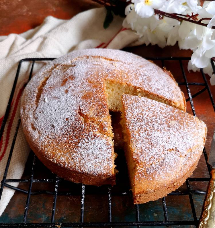 close up view of incredible moist, fluffy and egg less vanilla sponge cake sliced and dusted with powdered sugar
