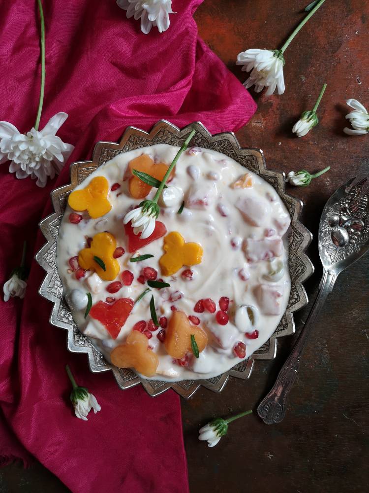 Overhead photo of fruit cream served on a silver plate with silver spoon and garnished with heart shaped watermelon, mango,musk melon and pomegranates, Fruit cream recipe 