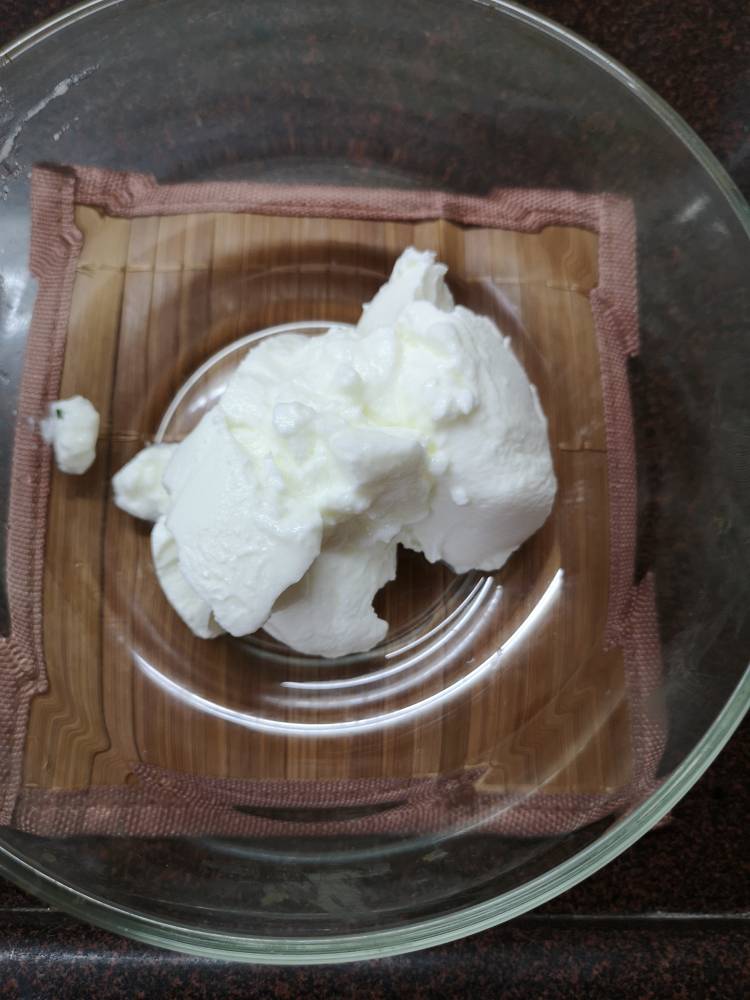 adding thick yogurt, curd to a bowl for Fruit cream recipe 