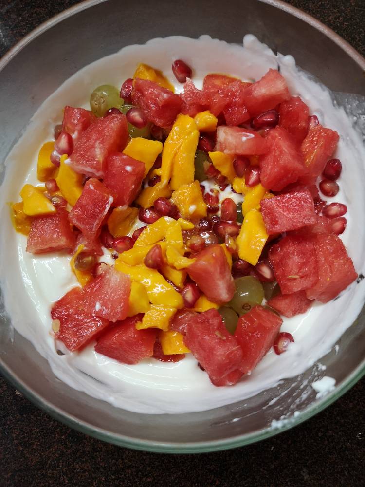 close up view of chopped mangoes, watermelon, grapes and pomegranates for fruit cream recipe