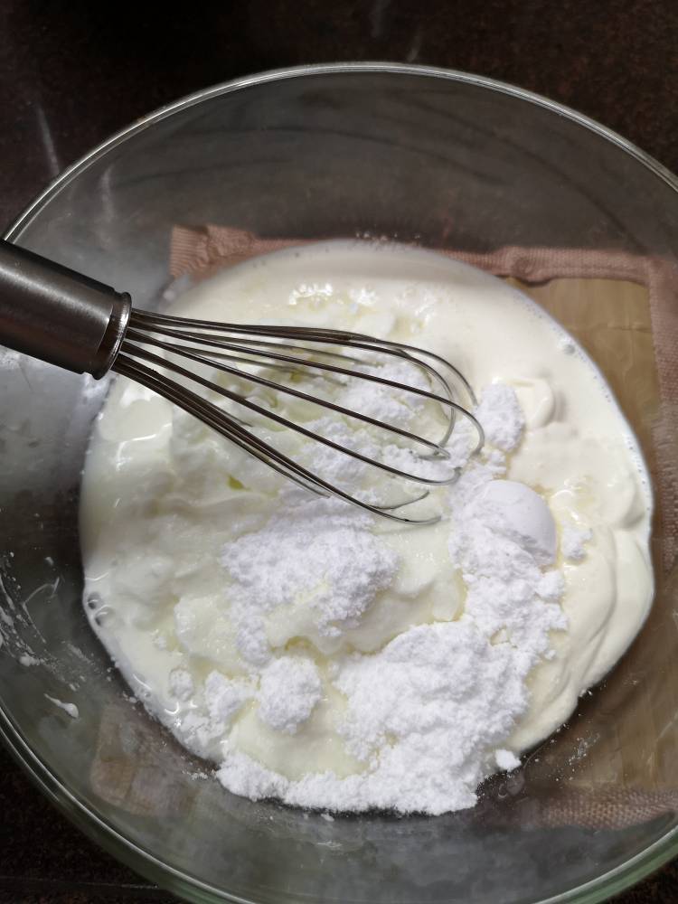 mixing icing sugar, yogurt and cream for Fruit cream recipe 