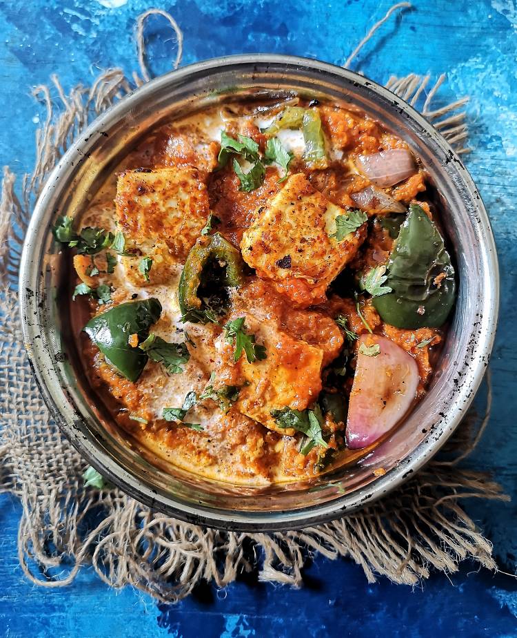 close up photo of paneer tikka masala served in a round bowl kept underneath a jute cloth on a blue board and garnished with fresh coriander leaves, How to make Restaurant Style Paneer Tikka Masala 