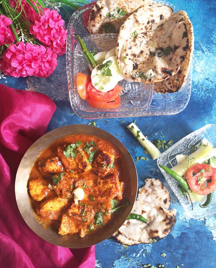 overhead photo of tawa paneer masala with gravy garnished with fresh coriander leaves, fresh cream, served with butter tandoori rotis and cucumber, tomato slices with green chilies, how to make restaurant style tawa paneer masala at home , recipe of tawa paneer masala