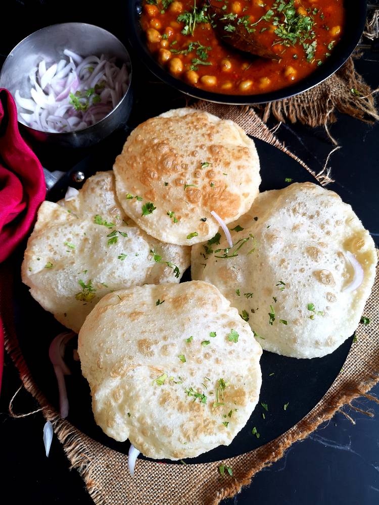 Close up view of Chole and fluffy Bhatura served with onion slices.
