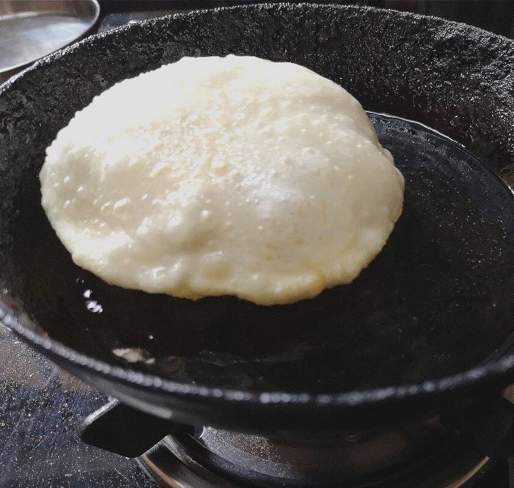 close up view of bhatura being fried in hot oil