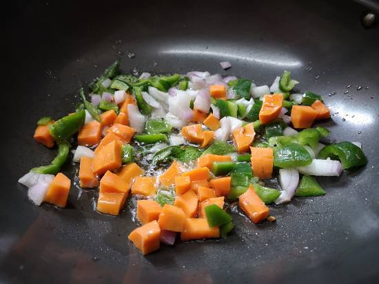 adding cut onions, carrots and capsicum along with mustard seeds, cumin seeds and curry leaves