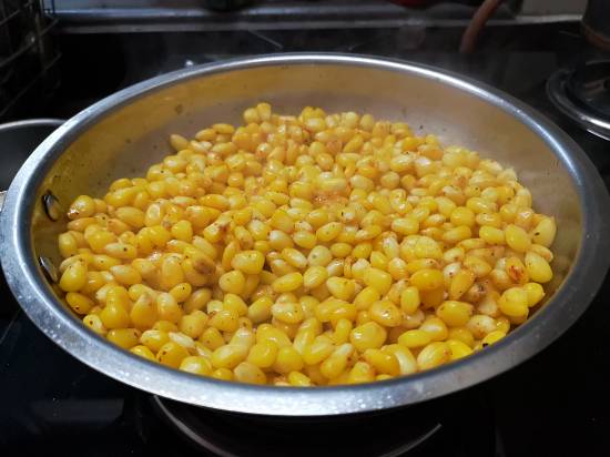 cooking buttered corn with butter on a medium flame