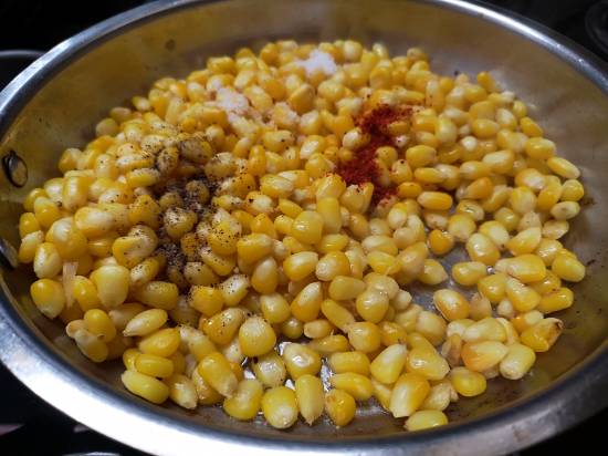 Add Kashmiri red chili powder, pepper powder, a bit of salt and mix it well in the corn