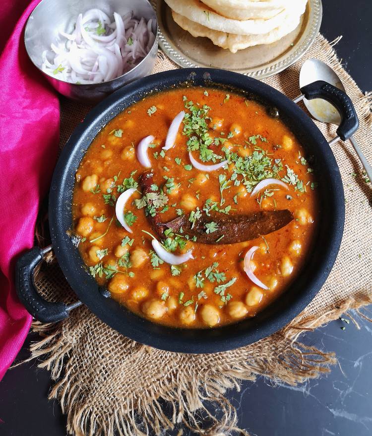 chole bhatue garnished with coriander leaves and sliced onions