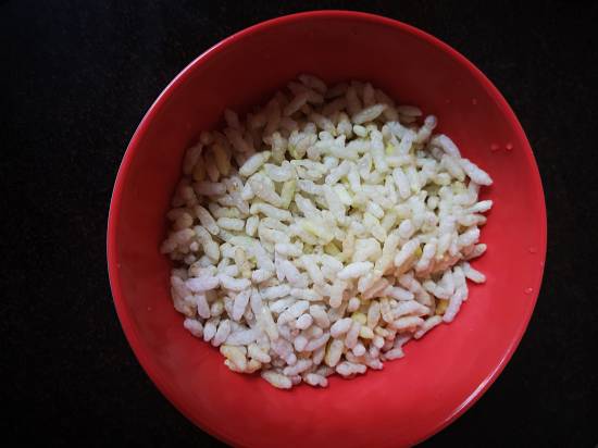 adding puffed rice mamra in a red bowl