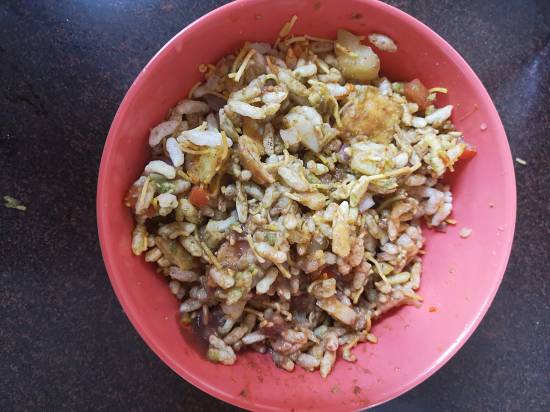 Mixing tamarind and dates chutney, coriander chutney, garlic chutney into the puffed rice mixture, how to make Dahi Bhel Recipe