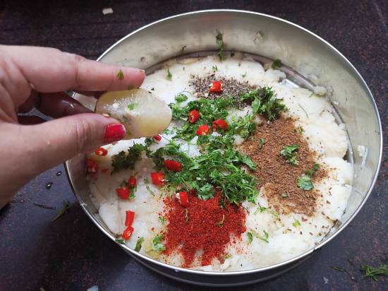 squeezing lime juice in mashed potatoes, with spices like black pepper, red chili powder and cumin powder for grilled potato sandwich
