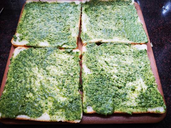 applying butter and coriander chutney on slices of bread for grilled potato sandwich