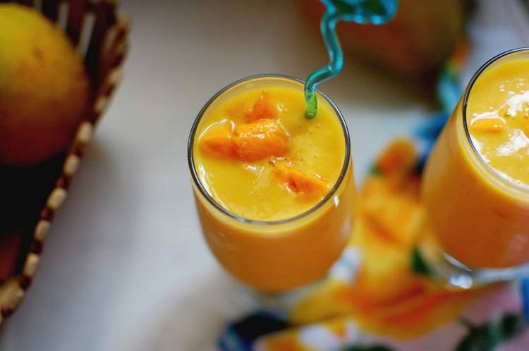 close up view of Mango Milkshake with mango chunks and blue straw