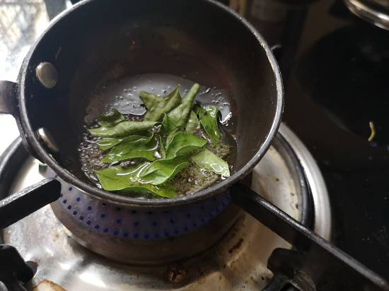 preparing tadka of Mysore Rasam with oil, mustard seeds, hing, and curry leaves