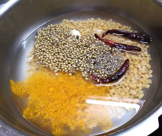 boiling toor dal along with coriander seeds, cumin seeds, turmeric powder, dry red chili, garlic and peppercorn for making mysore rasam 