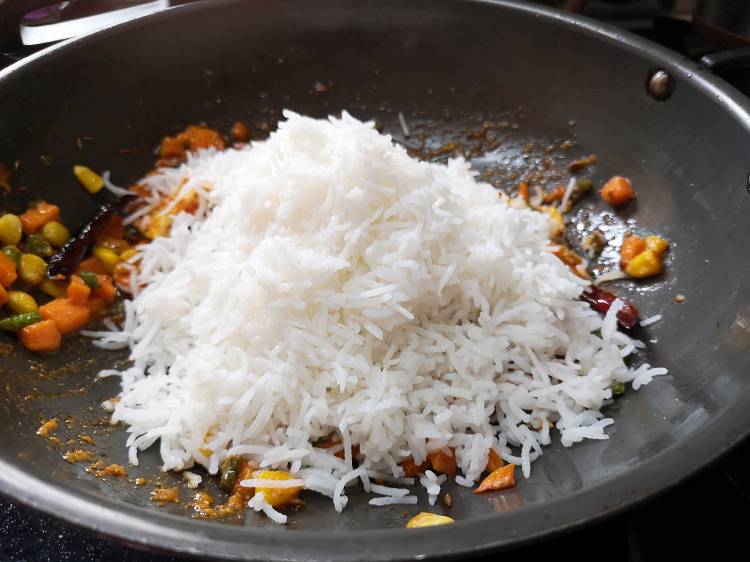 Adding cooked basmati rice in the kadhai of marinated paneer and cooked sweet corn, carrot and french beans, how to make paneer pulao