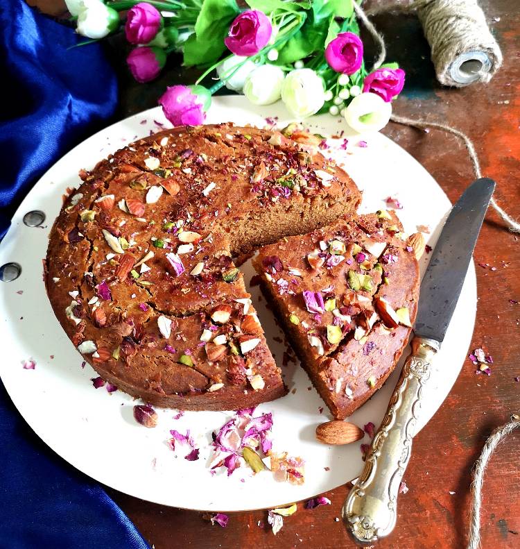 close up view of soft and crumbly parle g cake garnished with dry rose petals, almonds and pistachios, How to make Parle G cake