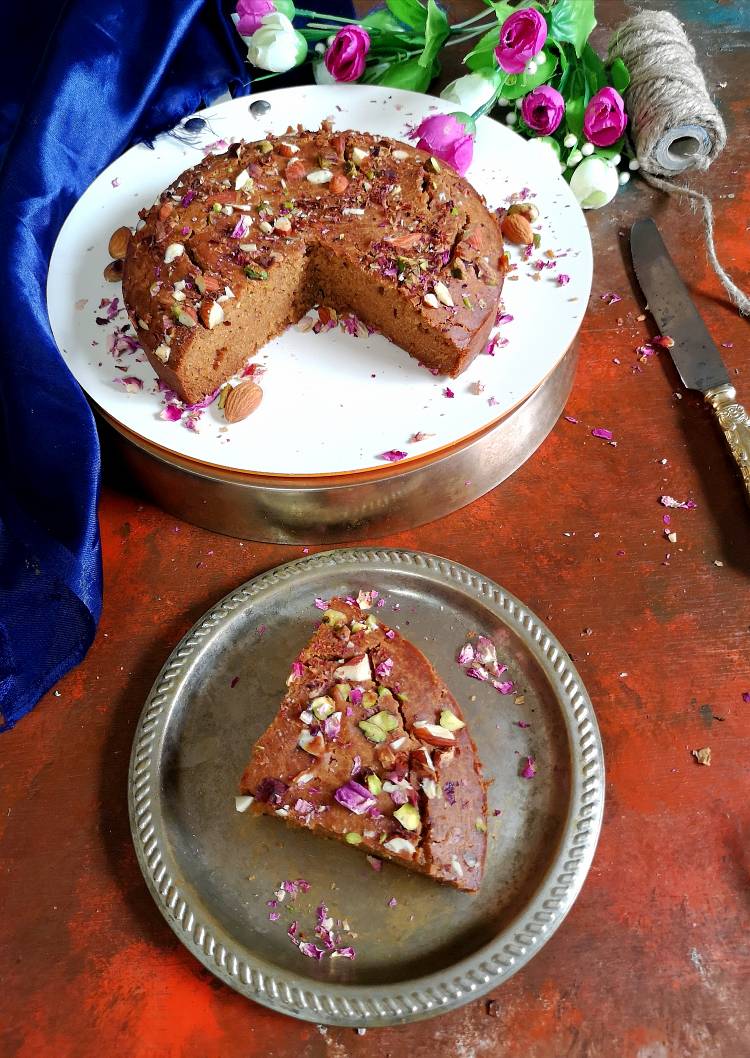 close up view of a slice of parle g biscuit cake garnished with almonds, pistachios and dry rose petals, How to make Parle G biscuitcake
