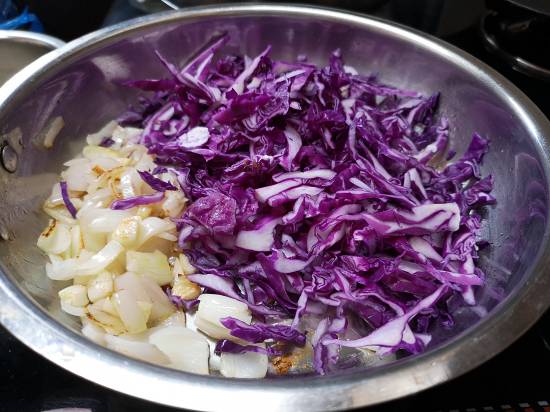 adding shredded purple cabbage to sauteed onion and garlic