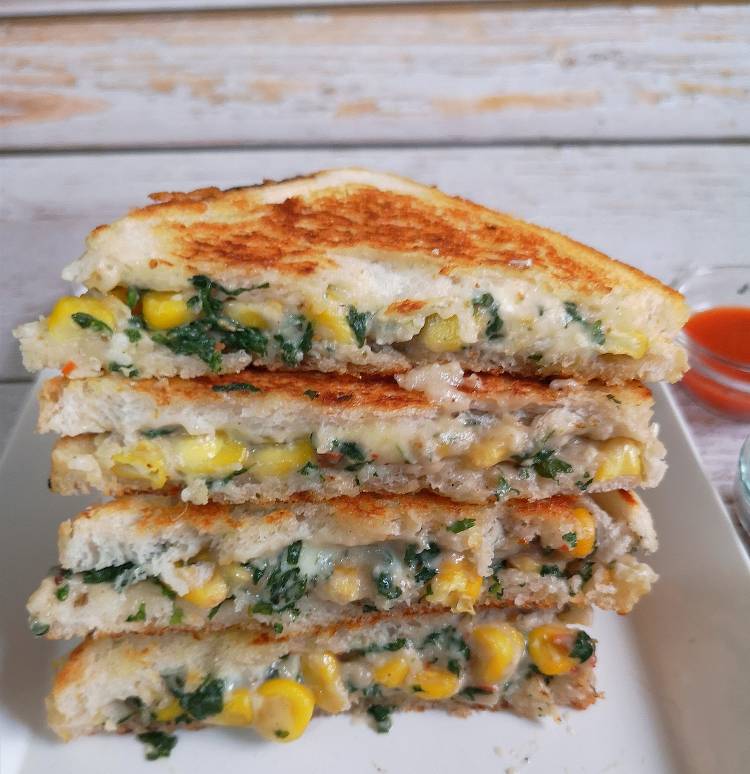 close up view of cut slices of spinach corn cheese sandwich ready to be served