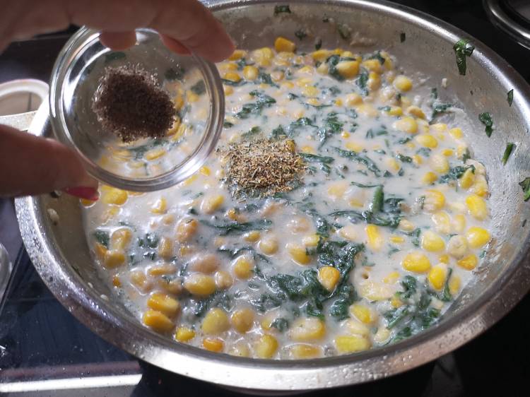 adding black pepper powder to sweet corn and spinach stuffing