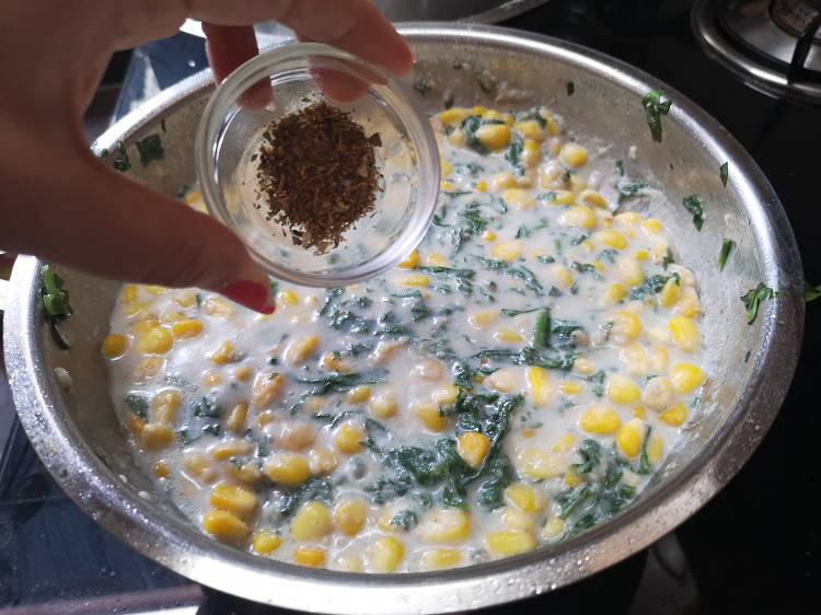 adding dry oregano to the creamy stuffing of spinach and sweet corn sandwich