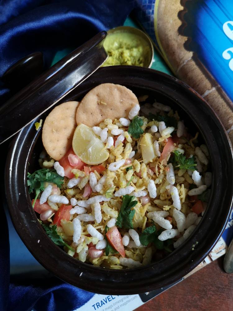close up view of sukha bhel served with papdis, sev and garnished with coriander leaves, pomegranates and a wedge of lemon