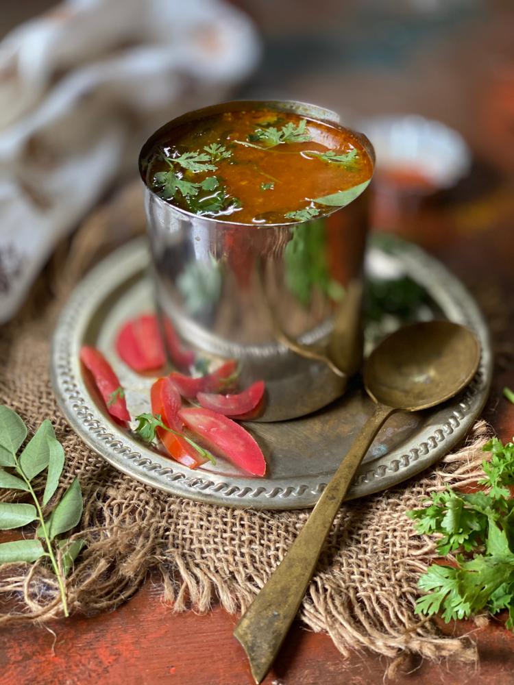 close up view of Tomato Rasam served in a steel tumbler, garnished with finely chopped coriander leaves , how to make Tomato Rasam without dal