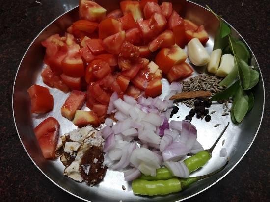all the ingredients for Tomato Rasam on a plate like garlic, onions, curry leaves, cumin seeds, pepper, tamarind, green chili. tomatoes,how to make tamato rasam