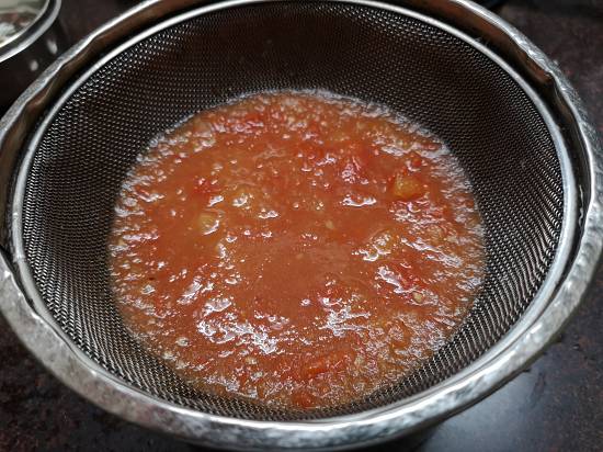 sieving tomato pulp into a strainer, how to make tomato rasam