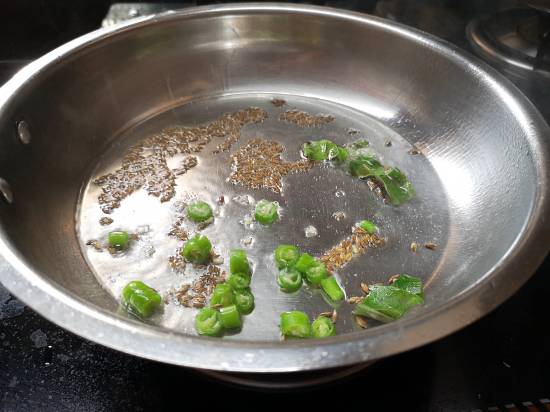 adding finely chopped green chilies and cumin into hot oil, Vrat Wali Sukhi Arbi Recipe