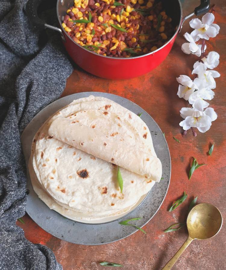 mexican flour tortillas with beans and corn casserole along with a spoon and flower in the background