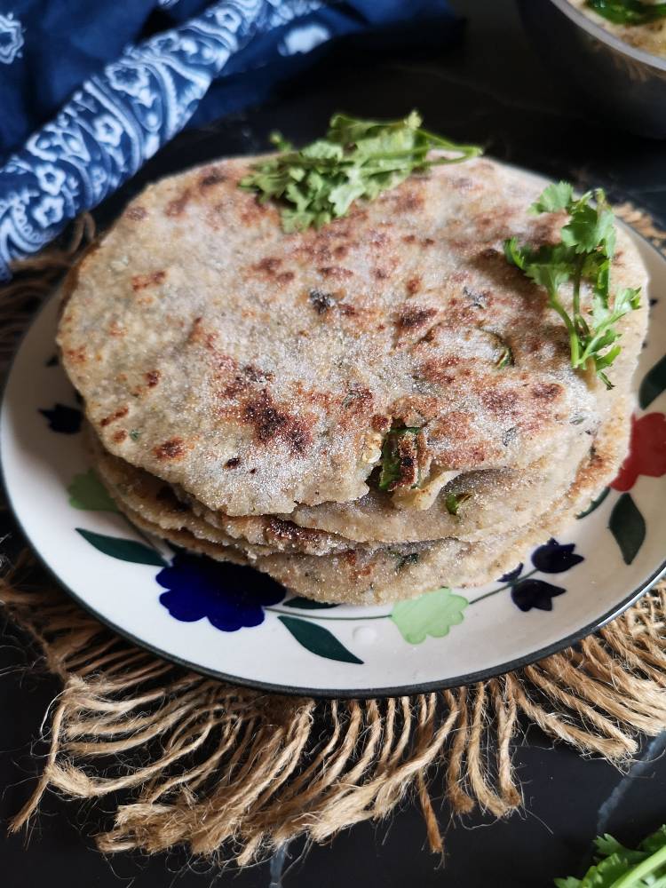 close up image of Vrat Wale Kuttu Parathas garnished with fresh coriander leaves served in a ceramic plate, Paratha Recipe with Buckwheat Flour for Navratri Vrat or Shravan Fasting