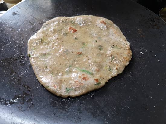 applying desi ghee on kuttu parathas, being cooked on an Iron Gridle