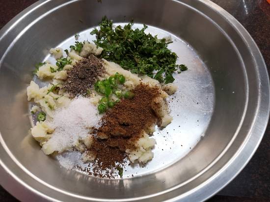 adding cumin powder, black pepper powder and coriander to the potato mixture for Vrat Wale Kuttu Parathas